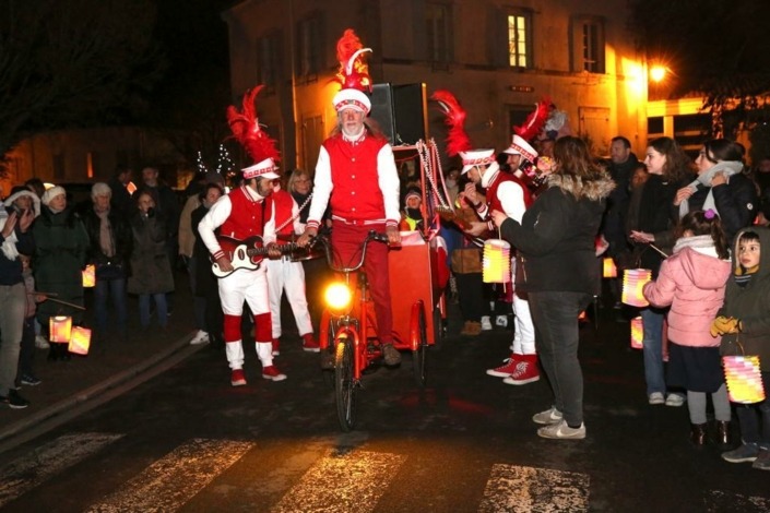 Les Chaussettes Rouges et leur tricycle lumineux sur la route entonnant des mélodies de Noël.
