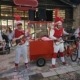 Les Chaussettes Rouges et leur tricycle jouant du rock yéyé des années 60 sur une place.