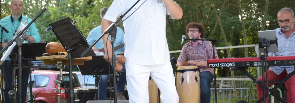 Le groupe de salsa Pacho Combo en concert sur scène en extérieur.