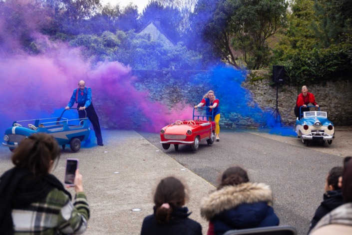Les 3 artistes de Le Grand Démanègement démarrent en fumée de couleur les voitures du manège.