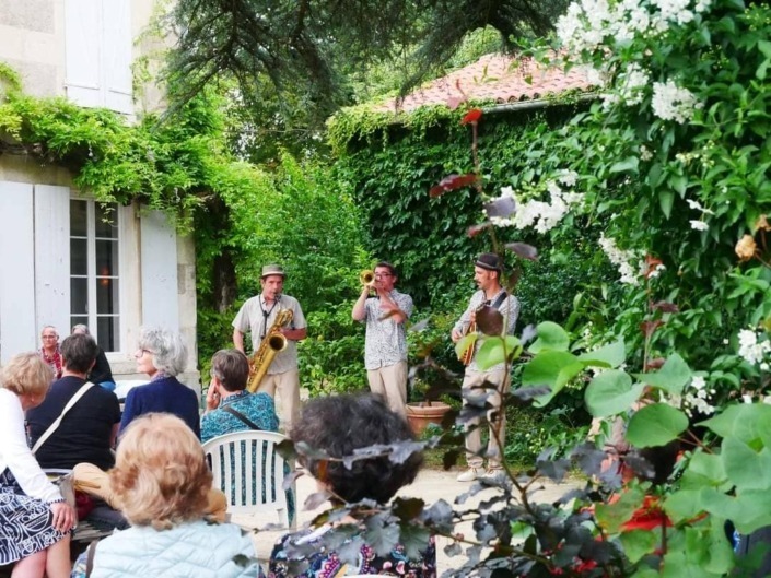 Le trio Lil'Brass Band déambulant dans le Domaine Coirier à Pissotte lors du festival Juste Eclos 2024 tout en jouant leur répertoire musical.