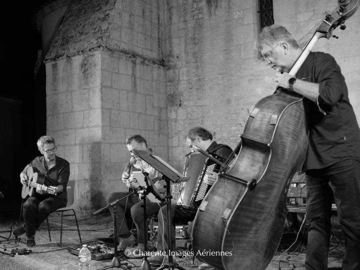 Concert en extérieur d'Anouman Swing Quartet où les 4 musiciens jouent des morceaux de swing manouche.