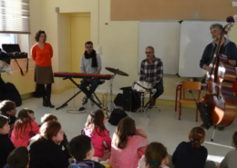 Les 4 artistes du spectacle musical jeune public Une trompette dans l'espace devant des enfants à l'école.
