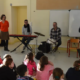 Les 4 artistes du spectacle musical jeune public Une trompette dans l'espace devant des enfants à l'école.