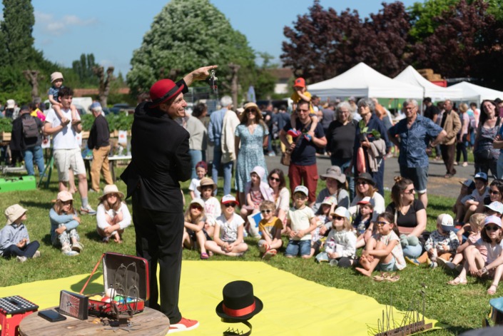 Un jongleur devant du public en plein air.