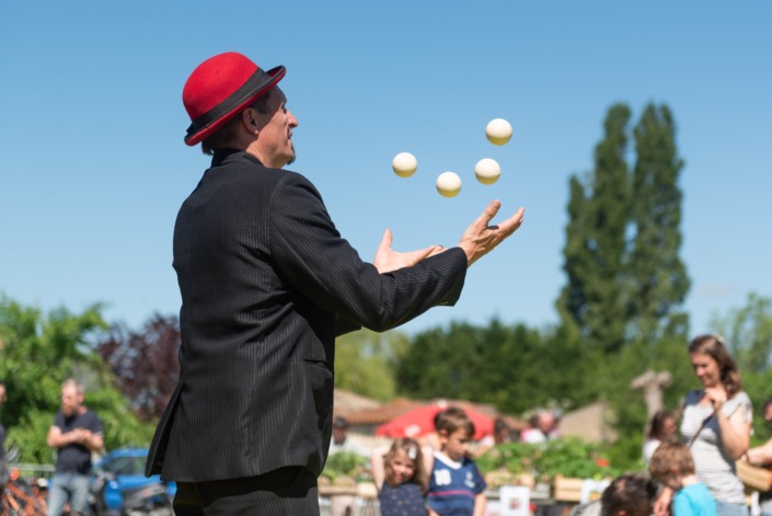 Un jongleur devant du public en plein air.